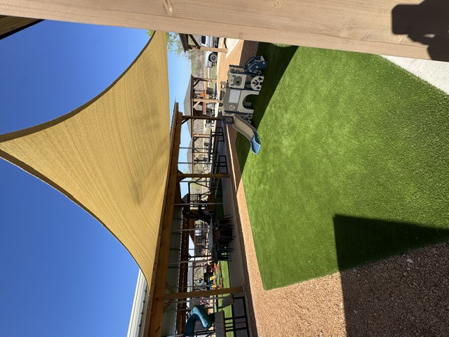 Shaded play area with artificial turf and a shade sail at The Playground @niederwald