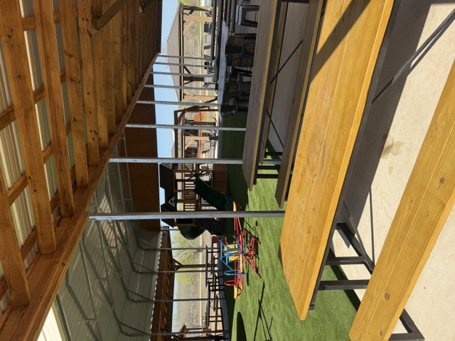 Shaded picnic tables under a pavilion at The Playground @niederwald